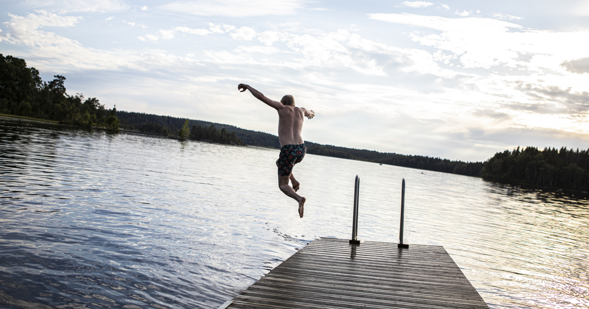 En man hoppar från en brygga ner i en sjö.