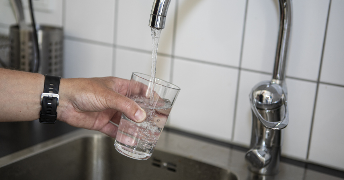 En person fyller ett glas vatten från en kran.