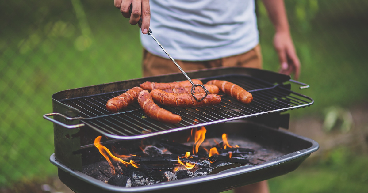 En man tillagar varmkorv på en grill.