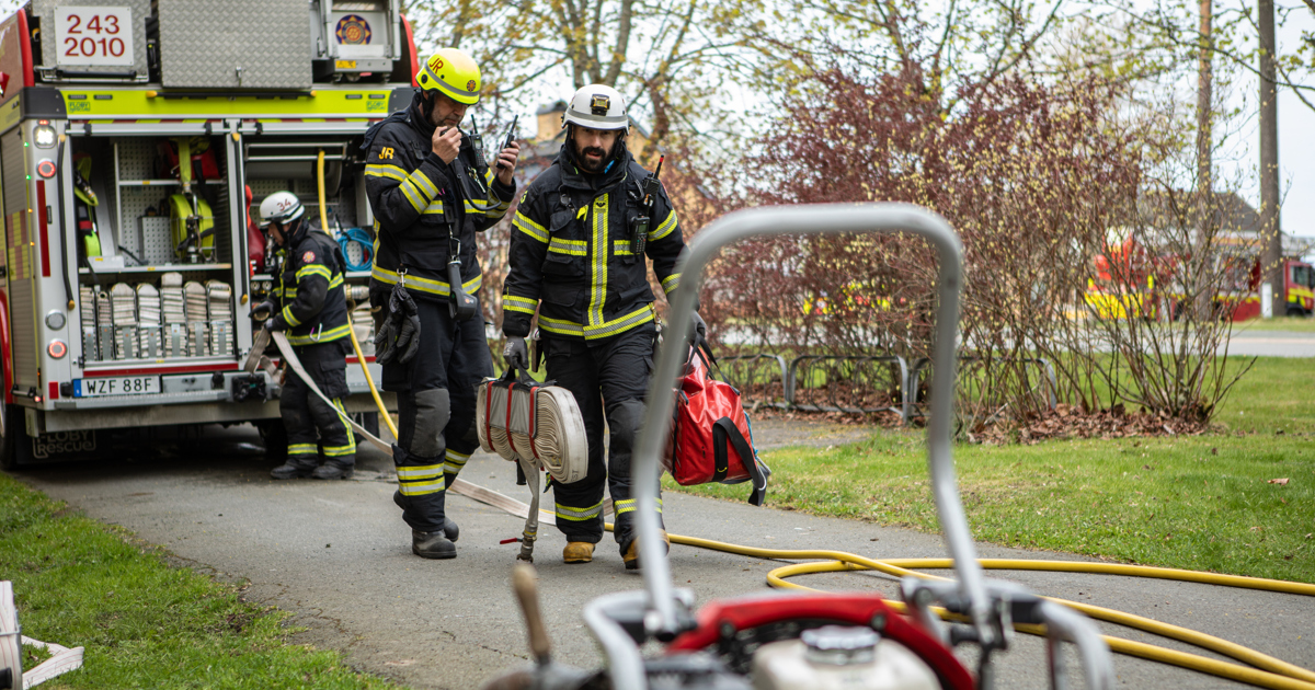 En grupp brandmän går längs en gata.