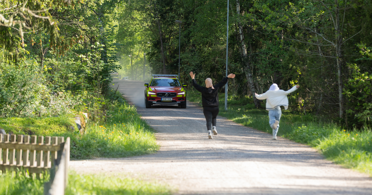 Några personer som springer längs en väg mot ett utryckningsfordon.